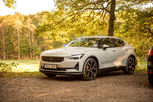 A white Polestar 2 by a park at fall