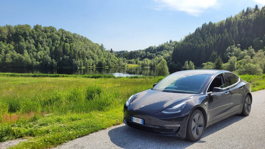 De magnifiques paysages sur la route en Norvège. Vue panoramique sur les environs de Leirvik. Une photo statique d'une voiture électrique Tesla Model 3. Champ vert et lac. Mise au point sélective