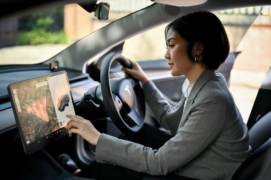 Une femme d'affaires asiatique séduisante qui utilise un système de navigation GPS et choisit une destination sur un écran de tableau de bord. Femme d'affaires sur un modèle Tesla 3